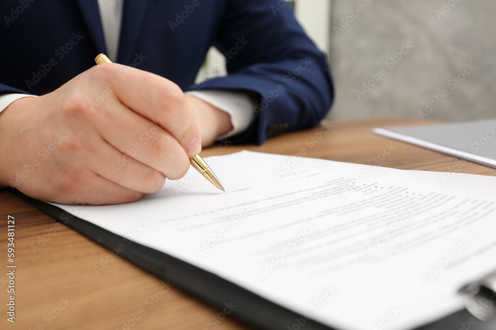 Sticker Man signing document at wooden table, closeup