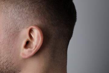 Man on grey background, closeup of ear