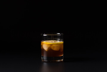 Bergamot Sour cocktail with ice cubes isolated on a black background