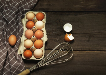 Fresh chicken eggs in a basket on a kitchen towel on a wooden table.