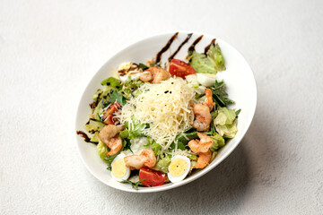 Seafood salad with bread croutons. Salad with shrimp, eggs, parmesan, lettuce, tomatoes on white plate. Caesar with seafood. Healthy diet. Low calorie food. Top view. White background. Copy space. 