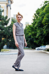 Portrait full length of pretty looking woman walking outdoors on city street and hair blowing in...