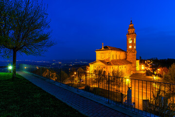 Illuminated parish church under blue morning sky in small italian town.