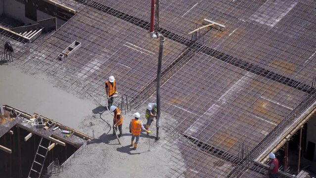 Builders pour concrete on a metal grate. Building a floor of a house