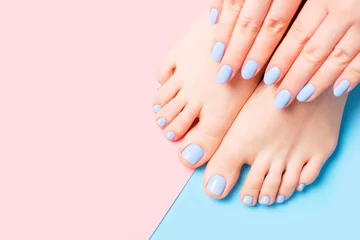 Selbstklebende Fototapeten Female hands and feet with light blue manicure and pedicure on a blue and pink background top view close-up. © TATIANA
