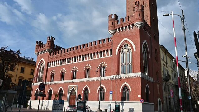 Asti, Italy, April 2023. Beautiful three-quarters footage of the Comentina tower, a perfectly preserved medieval structure. The bright red of the bricks characterizes it. Tilt. Travel destinations.