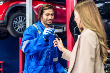Professional car technician mechanic in uniform work fixing vehicle car engine and maintenance repairing show car report and give car key to customer in auto service.Automobile customer service garage