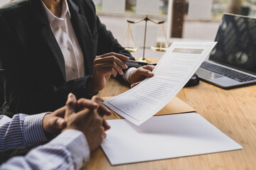 Female lawyer is explaining the terms of the legal contract document and asking the client to sign...