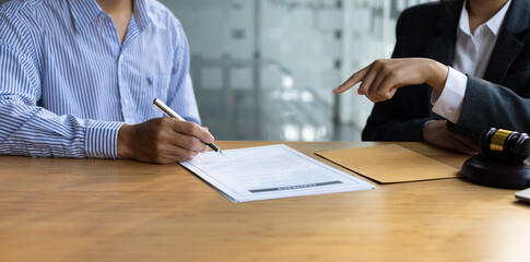 Female lawyer is explaining the terms of the legal contract document and asking the client to sign it properly.