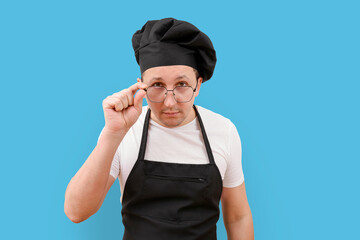 Portrait of chef in glasses looking at camera on blue background.