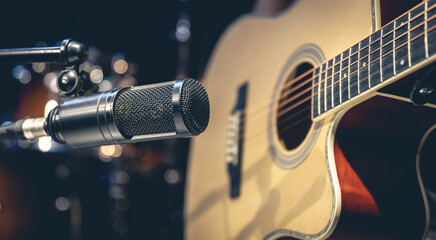 Acoustic guitar and microphone, recording in a music studio.