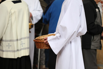 Ministrant zbiera datki do koszyka od wiernych w kościele katolickim. Ofiara.  - obrazy, fototapety, plakaty