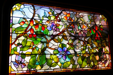 Close up of stained glass window with leaves and flowers on it. Generative AI.