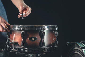A man plays the snare drum against a dark background.