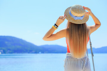 Mountain lake. Girl admires views and holding hands on the boater with tape. back view