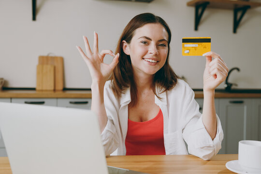 Young housewife woman n asual clothes using mobile cell phone credit bank card shopping online order delivery show ok eat breakfast cooking food in light kitchen at home alone Healthy diet concept