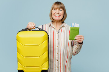 Happy raveler woman wears casual clothes hold suitcase passport ticket isolated on plain blue background studio Tourist travel abroad in free spare time rest getaway Air flight trip journey concept.