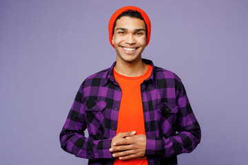 Young smiling confident happy fun cool man of African American ethnicity wearing casual shirt orange hat look camera hold hands isolated on plain pastel light purple color background studio portrait.