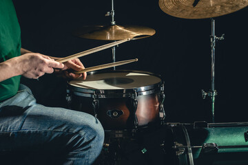 A man plays the snare drum against a dark background.
