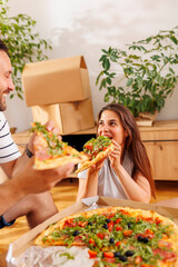 Couple taking a break eating pizza while moving in together