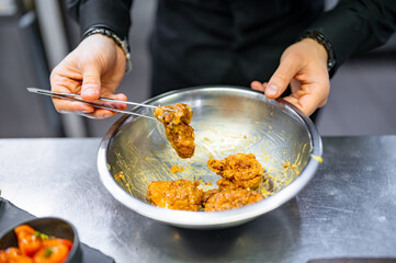 chef cooking chicken wings in a sauce in the kitchen
