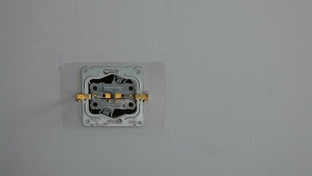 Male Electrician mounts a new socket in the wall.