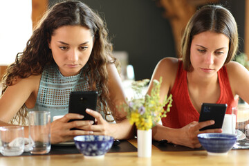 Friends in a restaurant ignoring each other using phones