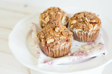 Seasonal muffins with cinnamon and almond slices on top on white background close up selective focus