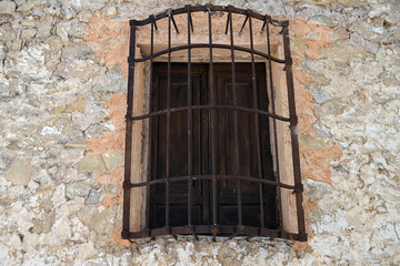 A rusty, old protection grid in front of a a church window in Spain.
