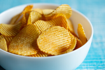 Close-up, a plate of potato chips on a blurred background.