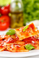 Ravioli pasta meal from Italy for lunch dish with fork and tomato sauce on a plate portrait format