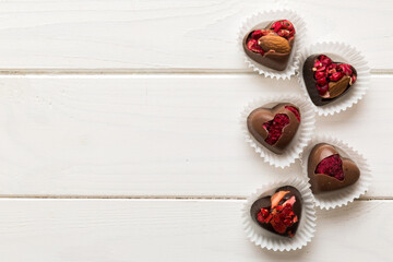chocolate sweets in the form of a heart with fruits and nuts on a colored background. top view with space for text, holiday concept
