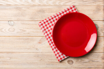 Top view on colored background empty round red plate on tablecloth for food. Empty dish on napkin...