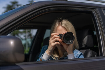 Paparazzi woman or girl sits in her car and takes pictures of famous person. Spy with camera in...