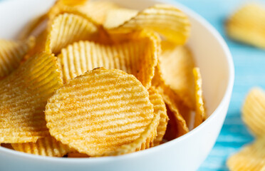 Close-up, a plate of potato chips on a blurred background.