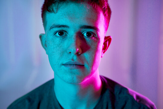 Sad young man with illuminated neon lighting on face