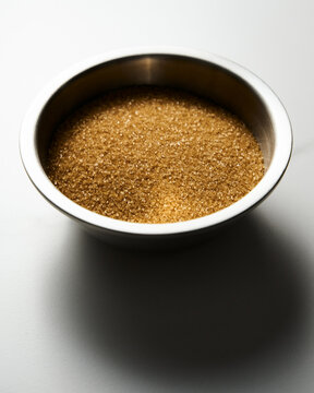 Brown sugar in metal bowl on white marble kitchen countertop background. 
