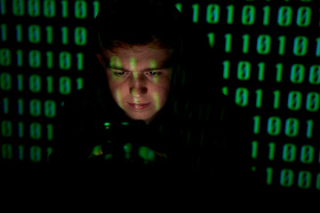 Young man wearing hood in front of binary numbers