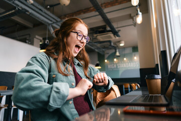 Successful young freelancer screaming at cafe