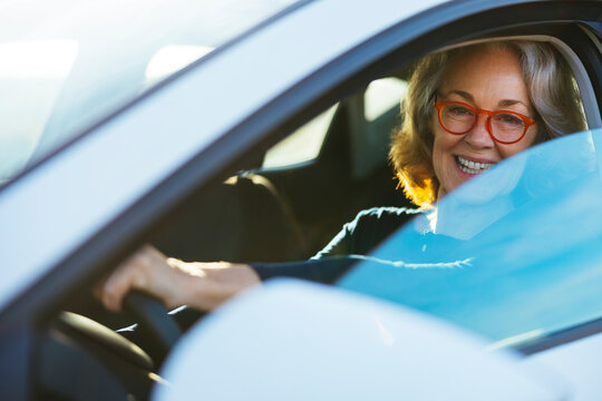 Happy mature woman driving car