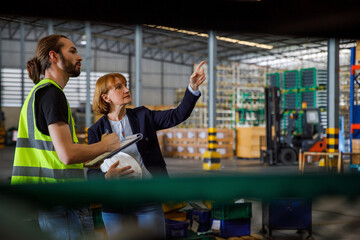 Manager pointing and discussing with colleague in factory
