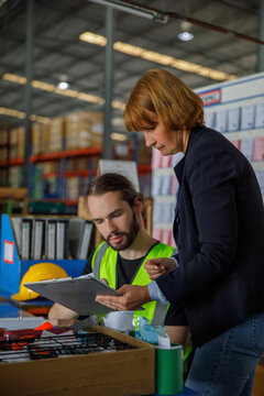 Manger discussing with colleague over checklist at warehouse