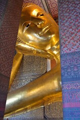 Gold gilded Reclining Buddha at Wat Pho with serene gaze, represent the Buddha's entry into Nirvana