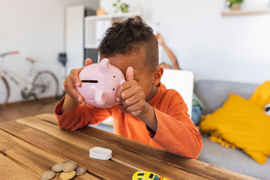 Boy opening piggy bank to count coins at home