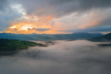 Fototapeta na wymiar Fog envelops the mountain forest. The rays of the rising sun break through the fog. drone view.