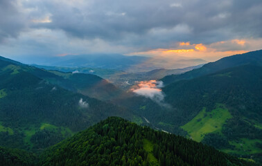 Obraz premium Fog envelops the mountain forest. The rays of the rising sun break through the fog. drone view.