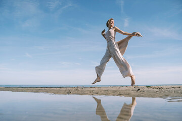 Reflection of happy woman jumping at beach