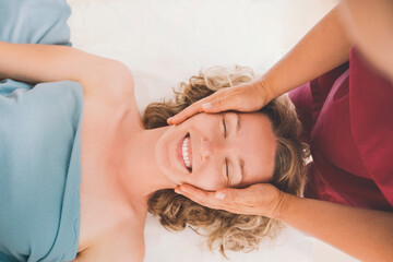 Therapist giving head massage to happy customer in salon