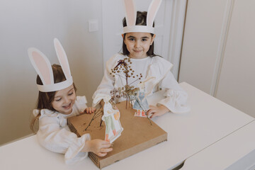Sisters wearing rabbit ears doing decorations for Easter at home