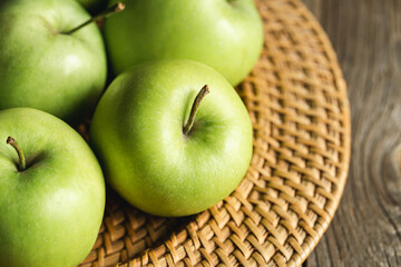 Close-up, green apples in a straw plate close-up.